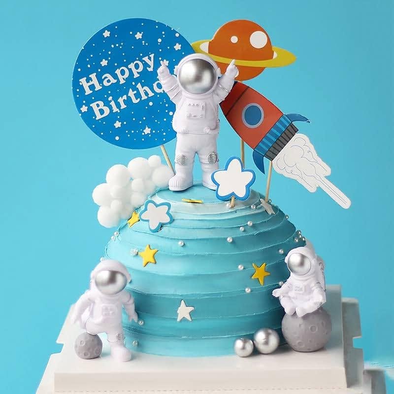 Blue ombre space-themed birthday cake with astronaut figures and a rocket topper