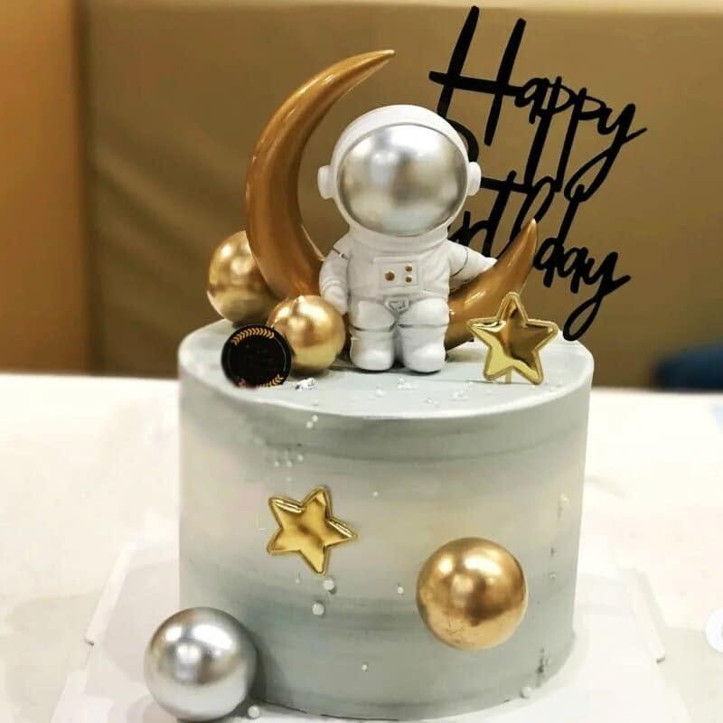 Grey marble space-themed birthday cake with an astronaut figurine and gold crescent moon
