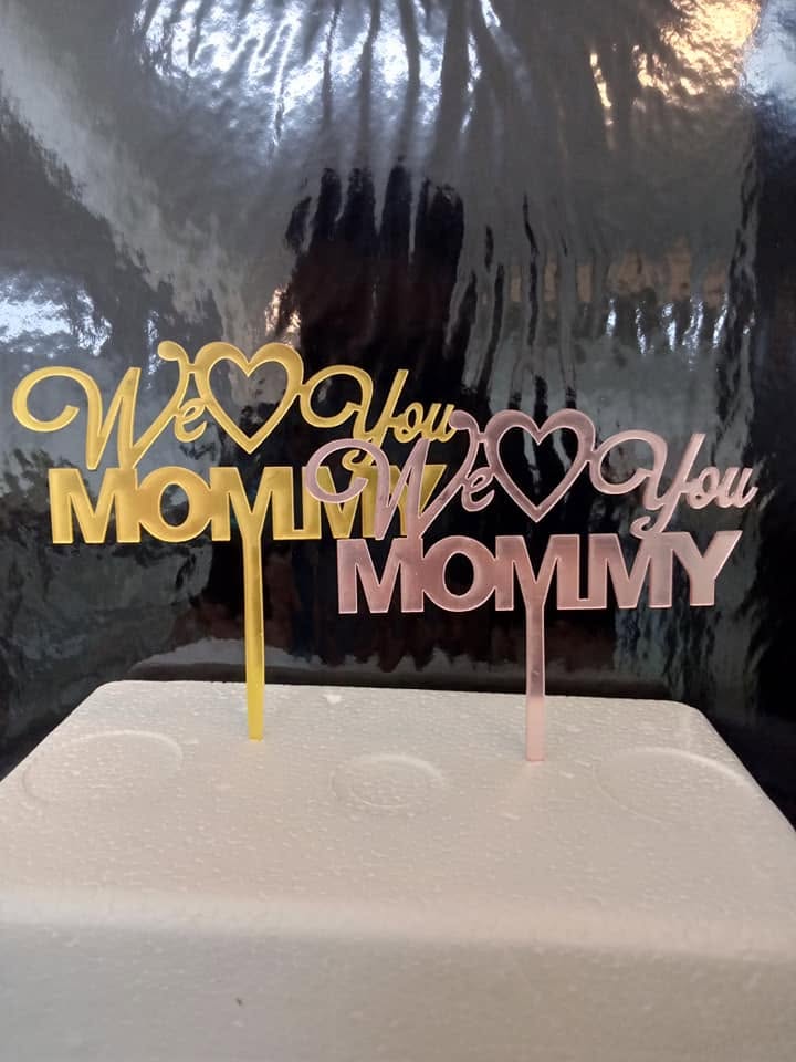 Gold and rose-gold acrylic cake toppers reading We Love You Mommy with heart cut-outs