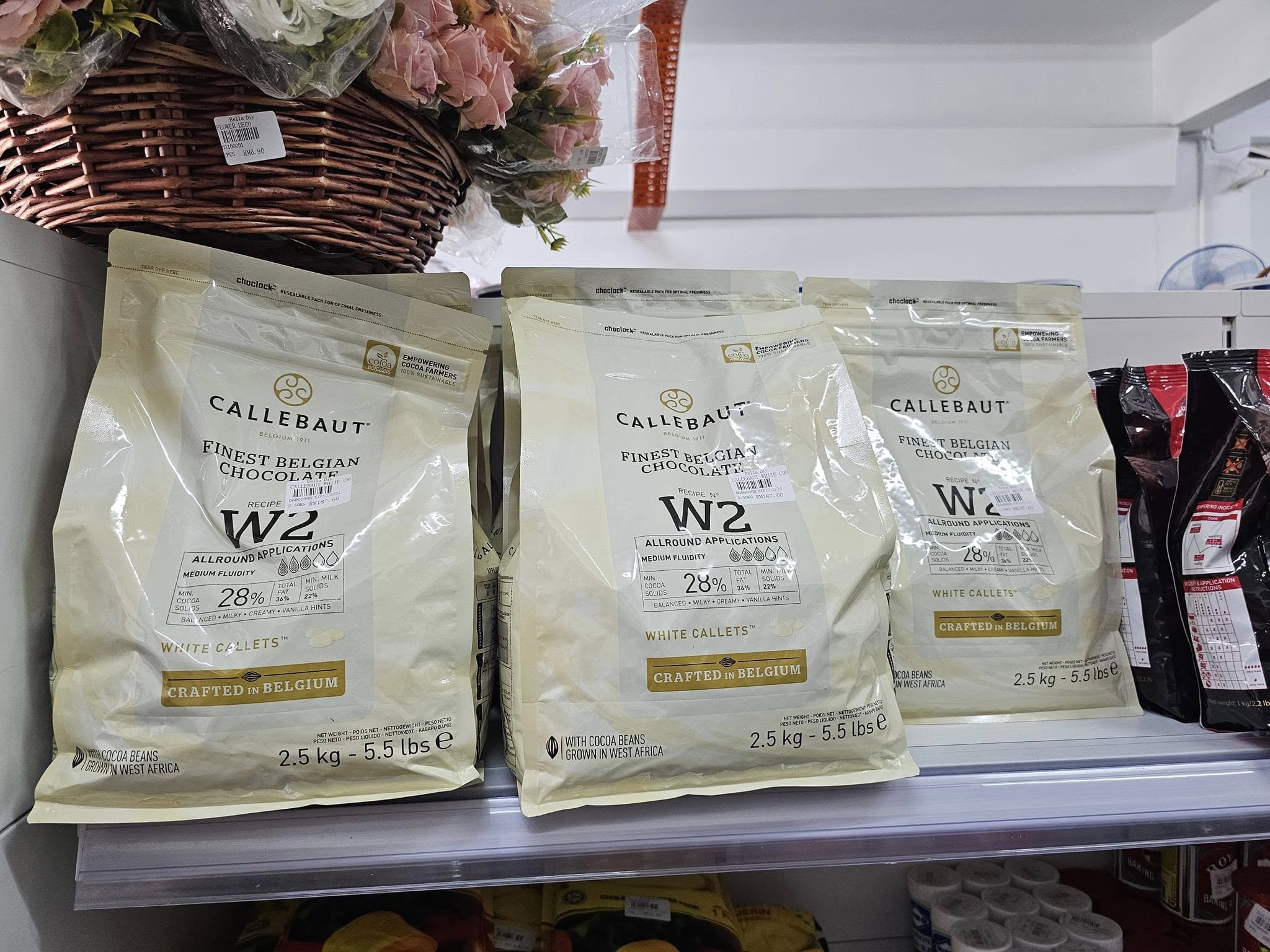 Bags of Belgian white chocolate callets stacked on a shop shelf