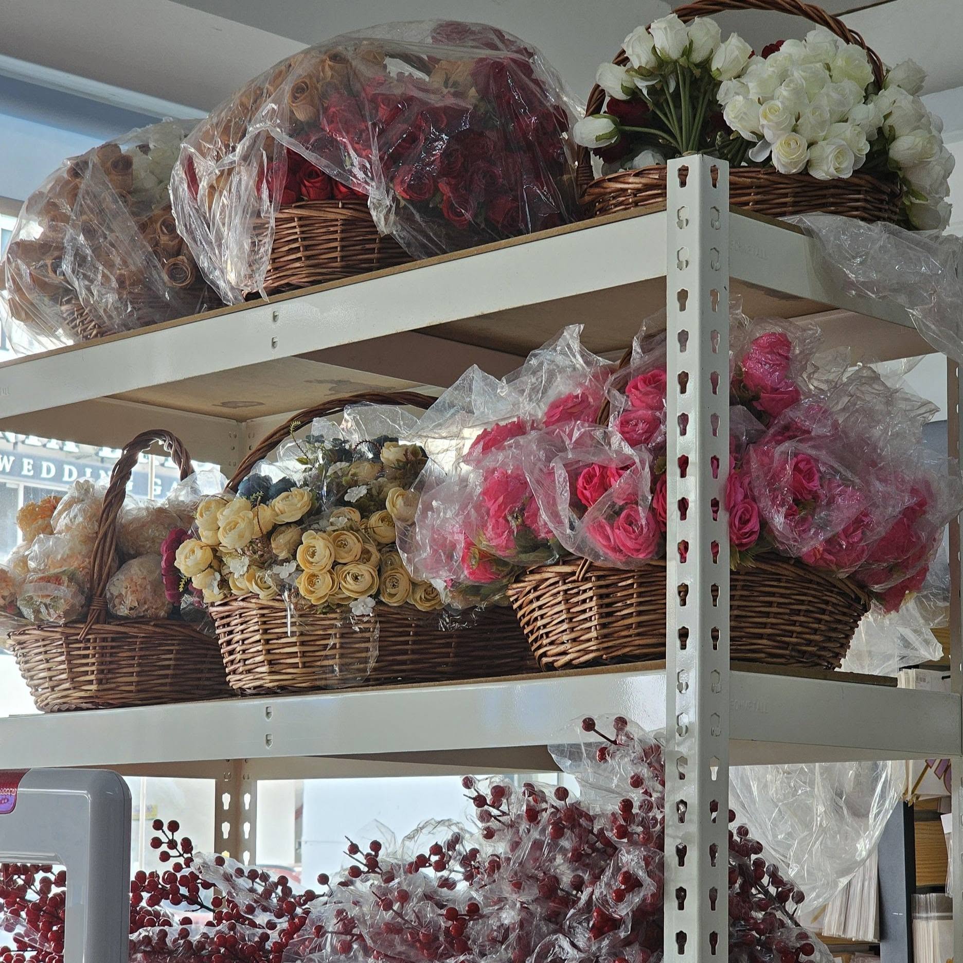 Wicker baskets of artificial roses displayed on a shop shelf near the storefront window